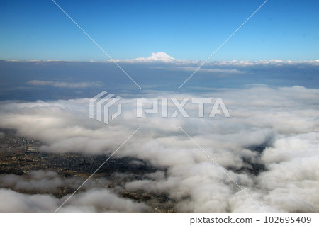 The sea of clouds seen from an airplane and the summit of Mt. Fuji thrust beyond it The sea of clouds seen from an airplane and the summit of Mt. Fuji thrust beyond it 102695409