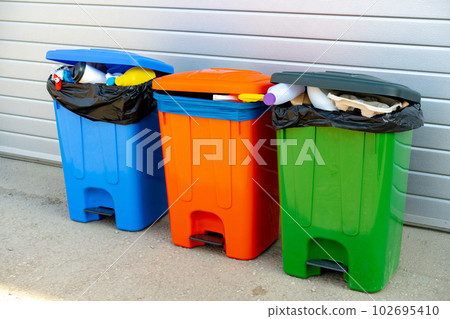 Three trash containers full of garbage near the building Three trash containers full of garbage near the building 102695410
