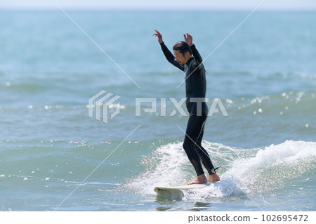 舉起雙手在衝浪板上的男人 102695472