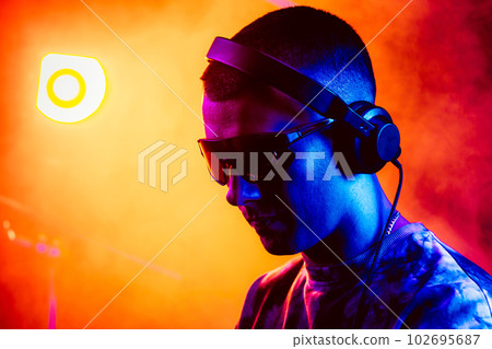 Club DJ playing music at party wearing sunglasses 102695687