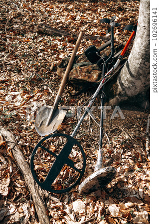 Metal detector device and spade on ground in forest 102696141