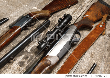 Many hunting rifles on weathered wooden surface Many hunting rifles on weathered wooden surface 102696172