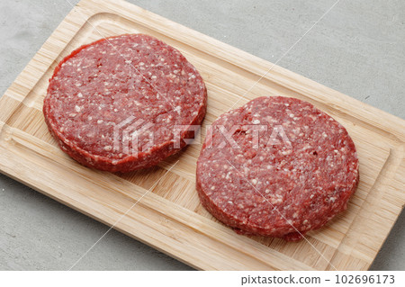 Raw beef burger patty on wooden board 102696173