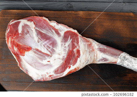 Raw beef leg on brown wooden board Raw beef leg on brown wooden board 102696182