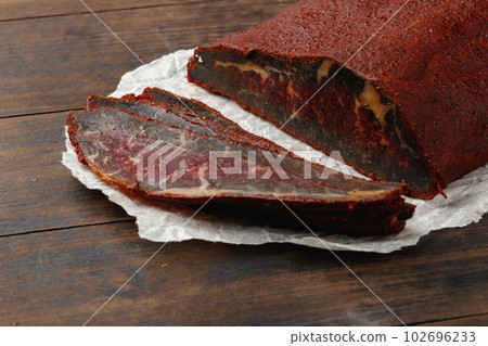 Sliced basturma meat on brow wooden background Sliced basturma meat on brow wooden background 102696233