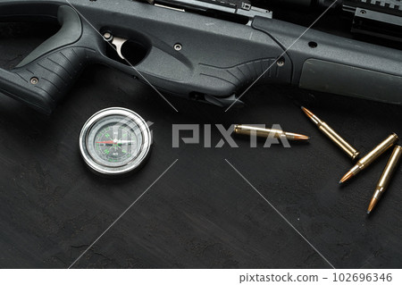 Hunting rifle and cartridges on dark wooden background Hunting rifle and cartridges on dark wooden background 102696346