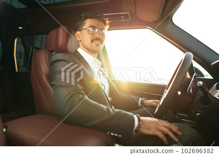 Young businessman in elegant suit driving luxury car Young businessman in elegant suit driving luxury car 102696382