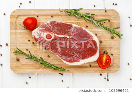 Raw lamb steak on board on white wooden table 102696461