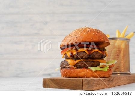 Double cheeseburger served on wooden board against white blurred background 102696518
