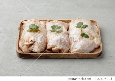 Raw chicken carcass on wooden plate close up 102696991