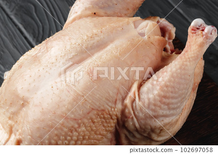 Raw chicken carcass on wooden plate close up Raw chicken carcass on wooden plate close up 102697058