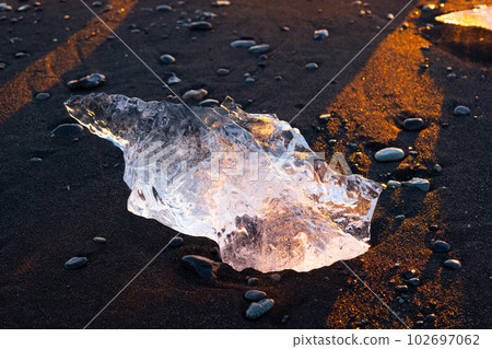 Icebergs Shining on Black Volcanic Sand at Sunset. Clear Ice Crashed by Ocean Waves. Famous Tourist Location in North Europe Country. Diamond Beach in Iceland. Travel Destination. High Resolution. 102697062