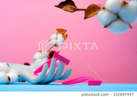 Pink disposable razors and cotton flower on blue paper 102697447