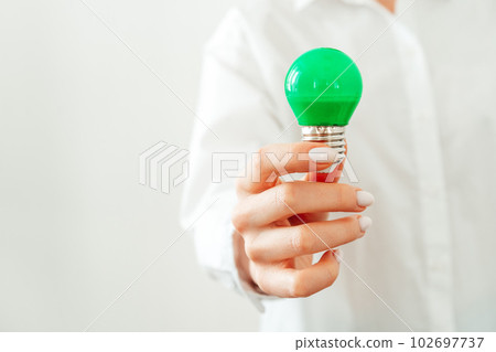 Woman in white shirt holding light bulb in hand Woman in white shirt holding light bulb in hand 102697737