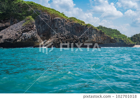 Rock formation on the ocean near the Tanjung Kasap or Cape Kasap, Pacitan, Indonesia. Taken from a moving boat. Rock formation on the ocean near the Tanjung Kasap or Cape Kasap, Pacitan, Indonesia. Taken from a moving boat. 102701018