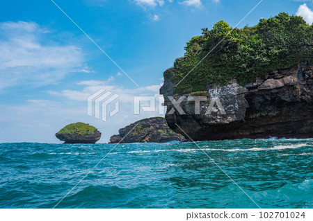 Rock formation on the ocean near the Tanjung Kasap or Cape Kasap, Pacitan, Indonesia. Taken from a moving boat. Rock formation on the ocean near the Tanjung Kasap or Cape Kasap, Pacitan, Indonesia. Taken from a moving boat. 102701024