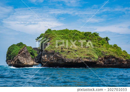 Rock formation on the ocean near the Tanjung Kasap or Cape Kasap, Pacitan, Indonesia. Taken from a moving boat. Rock formation on the ocean near the Tanjung Kasap or Cape Kasap, Pacitan, Indonesia. Taken from a moving boat. 102701033