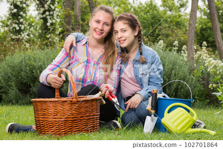 young mother and dauther with gardening tools in outdoors young mother and dauther with gardening tools in outdoors 102701864