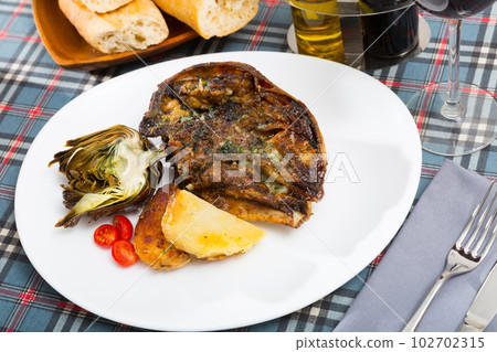 Cabeza de cordero - spanish dish. Lamb head with artichoke, tomatoes and potatoes 102702315