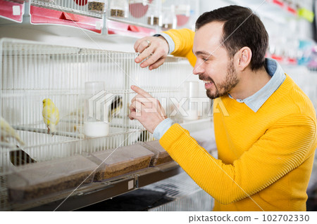 Smiling man choosing pretty bird 102702330
