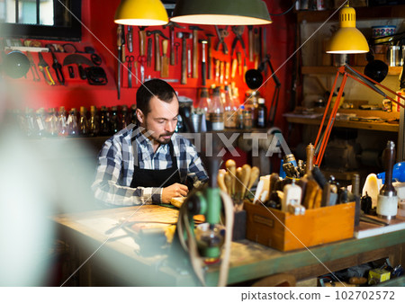 Worker processing leather for belt 102702572