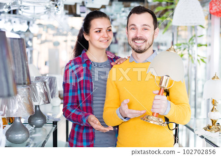 Young woman and man in shop of home appliances are choosing night lamp 102702856