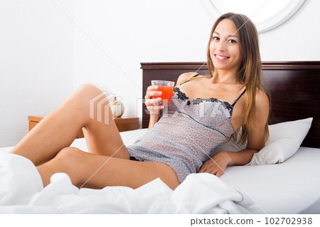 woman drinking juice in bed 102702938