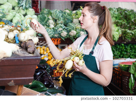 Smiling seller woman is demonstraiting beet in the market. 102703331