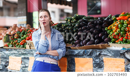 Woman choosing aubergine in market Woman choosing aubergine in market 102703493