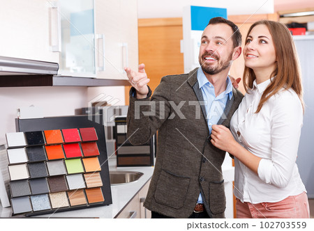 Smiling couple choosing material for kitchen furniture Smiling couple choosing material for kitchen furniture 102703559