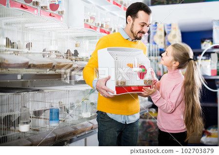 Father and daughter enjoying their purchase of canary bird in pet shop 102703879