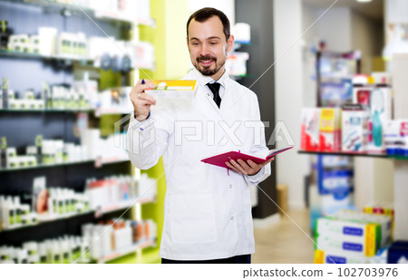 Male pharmacist checking assortment of drugs 102703976