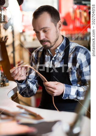 Hard-working man demonstrating his workplace in leather workshop 102704058