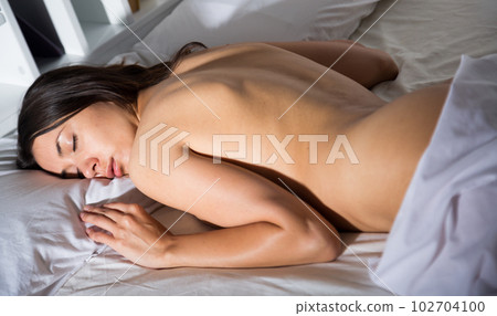 Seductive nude young sexy girl sleeping on white sheet in bed 102704100