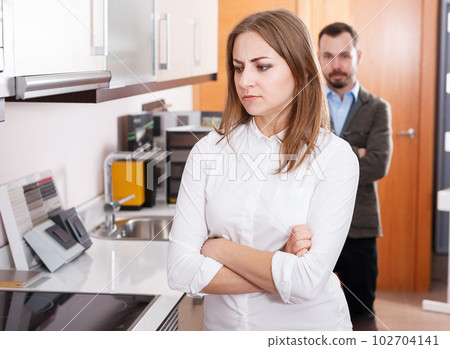 Upset girl with husband in kitchen furniture salon Upset girl with husband in kitchen furniture salon 102704141