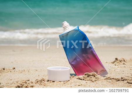 Used cosmetic sunscreen tube on sea shore. 102709791