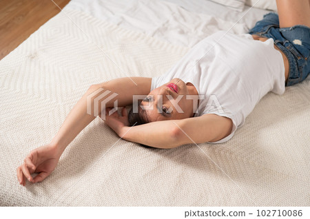 Caucasian transgender man lies on bed. Gay posing in the bedroom. Caucasian transgender man lies on bed. Gay posing in the bedroom. 102710086
