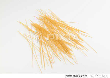 Spaghetti spread out on a white surface. 102711665