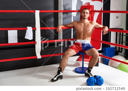 Tired male boxer sitting in the corner of the ring 102712540