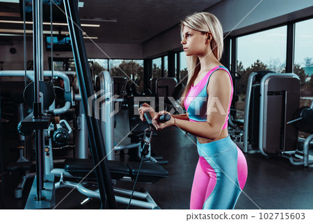 Young fitness woman execute exercise with exercise-machine Cable Crossover in gym Young fitness woman execute exercise with exercise-machine Cable Crossover in gym 102715603