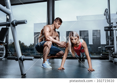 Fitness instructor exercising with his client at the gym. Fitness instructor exercising with his client at the gym. 102715610