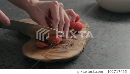 man slicing cherry tomatoes on olive board man slicing cherry tomatoes on olive board 102717435