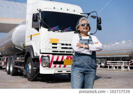 Business owner standing in front of oil truck after performing a pre-trip inspection on a truck. Concept of preventive maintenance. Business owner standing in front of oil truck after performing a pre-trip inspection on a truck. Concept of preventive maintenance. 102717539