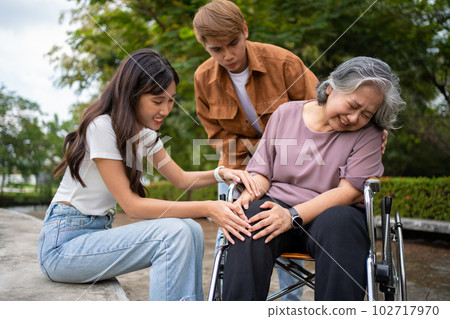 Asian careful caregiver or nurse taking care of the patient is hurting knee in wheelchair. Concept of happy retirement with care from caregiver and Savings and senior health insurance, a Happy family Asian careful caregiver or nurse taking care of the patient is hurting knee in wheelchair. Concept of happy retirement with care from caregiver and Savings and senior health insurance, a Happy family 102717970