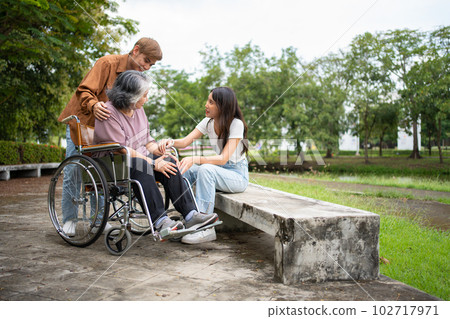 Asian careful caregiver or nurse taking care of the patient is hurting knee in wheelchair. Concept of happy retirement with care from caregiver and Savings and senior health insurance, a Happy family Asian careful caregiver or nurse taking care of the patient is hurting knee in wheelchair. Concept of happy retirement with care from caregiver and Savings and senior health insurance, a Happy family 102717971