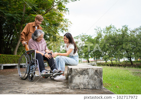 Asian careful caregiver or nurse taking care of the patient is hurting knee in wheelchair. Concept of happy retirement with care from caregiver and Savings and senior health insurance, a Happy family Asian careful caregiver or nurse taking care of the patient is hurting knee in wheelchair. Concept of happy retirement with care from caregiver and Savings and senior health insurance, a Happy family 102717972
