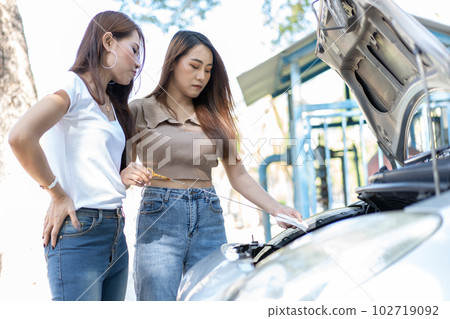 Two Asian people try to check the car engine and wait for assistance after a car breakdown on street. Concept of a vehicle engine problem or accident and emergency help from a Professional mechanic Two Asian people try to check the car engine and wait for assistance after a car breakdown on street. Concept of a vehicle engine problem or accident and emergency help from a Professional mechanic 102719092