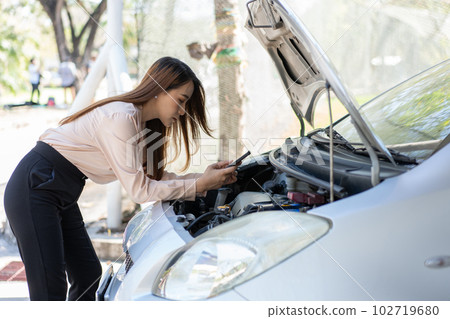 Angry Asian woman using a smartphone VIDEO conference for assistance after a car breakdown on street. Concept of a vehicle engine problem or accident and emergency help from a Professional mechanic Angry Asian woman using a smartphone VIDEO conference for assistance after a car breakdown on street. Concept of a vehicle engine problem or accident and emergency help from a Professional mechanic 102719680
