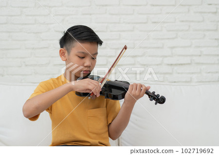 A Little Asian kid playing and practice violin musical string instrument against in home, Concept of Musical education, Inspiration, Teenager art school student. A Little Asian kid playing and practice violin musical string instrument against in home, Concept of Musical education, Inspiration, Teenager art school student. 102719692