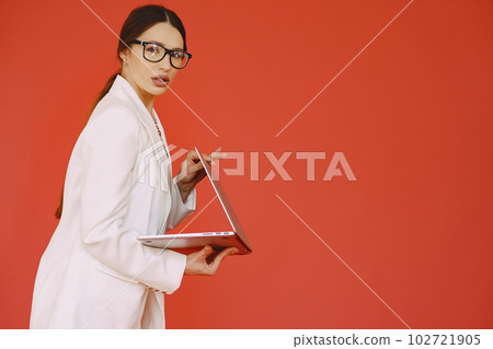 Woman in a studio. Lady with a laptop. Brunette in a white suit. 102721905